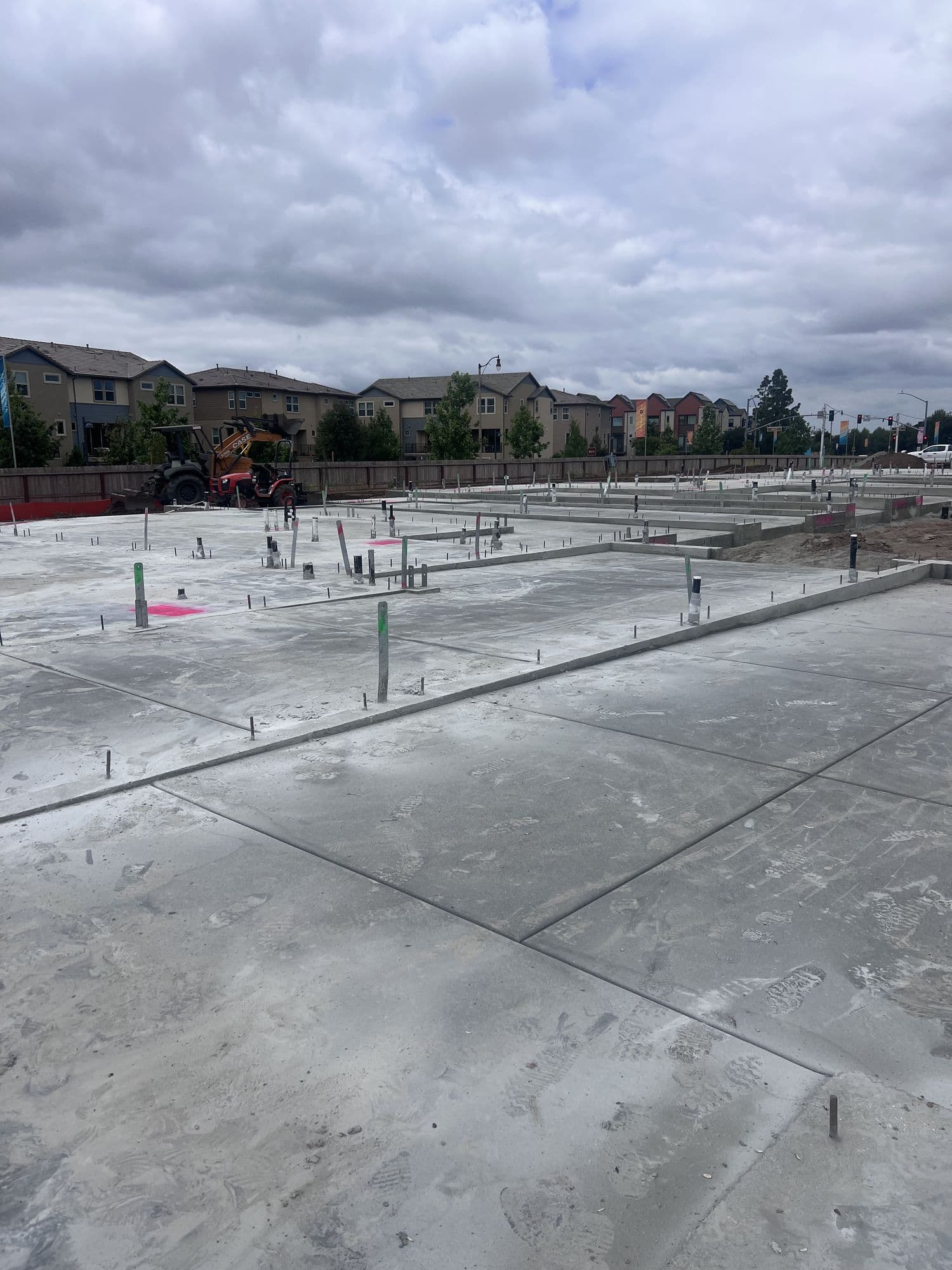 Freshly poured concrete slab foundations with plumbing stub-outs and layout markings