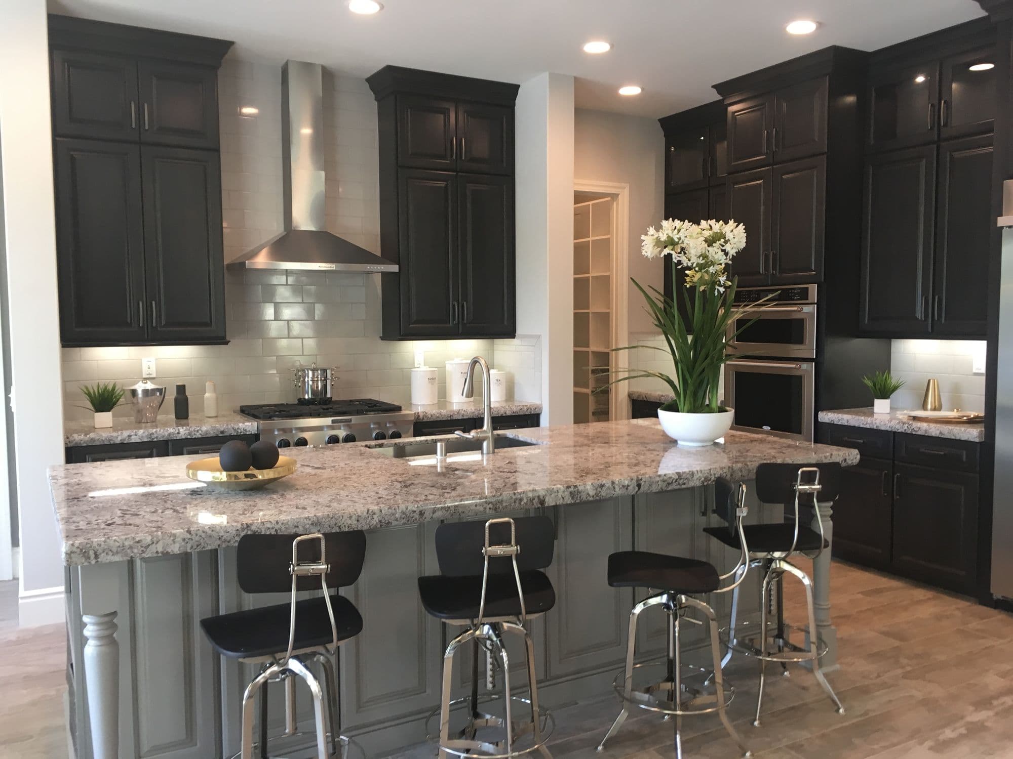 A finished model-home kitchen with dark cabinetry and a granite island