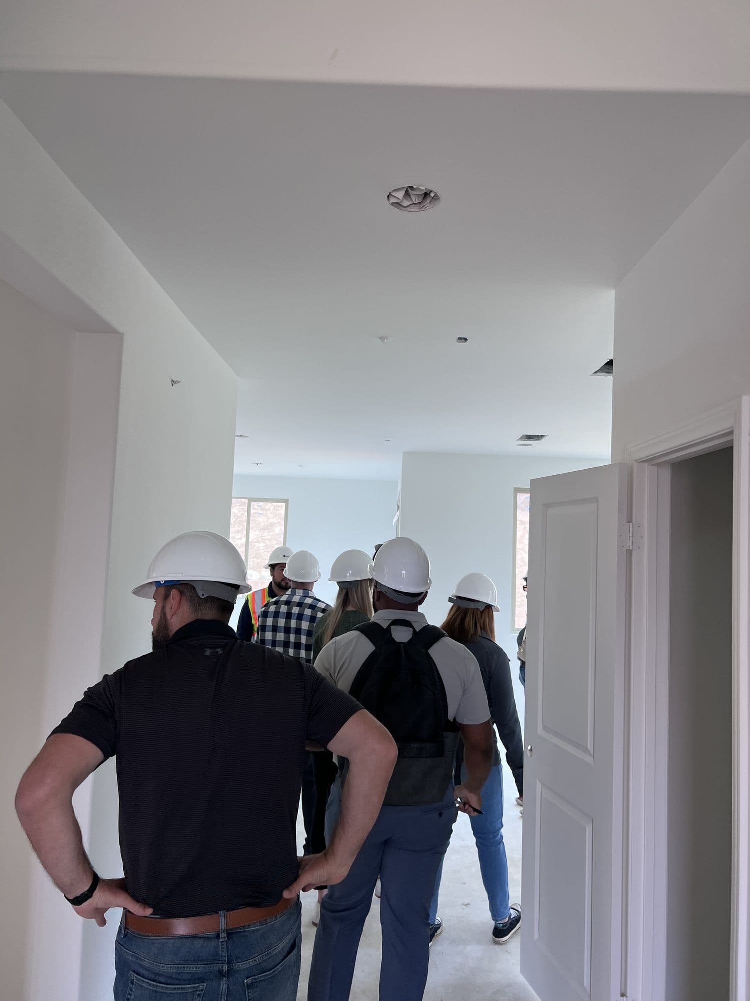 A group in hard hats walking through the interior of a home under construction